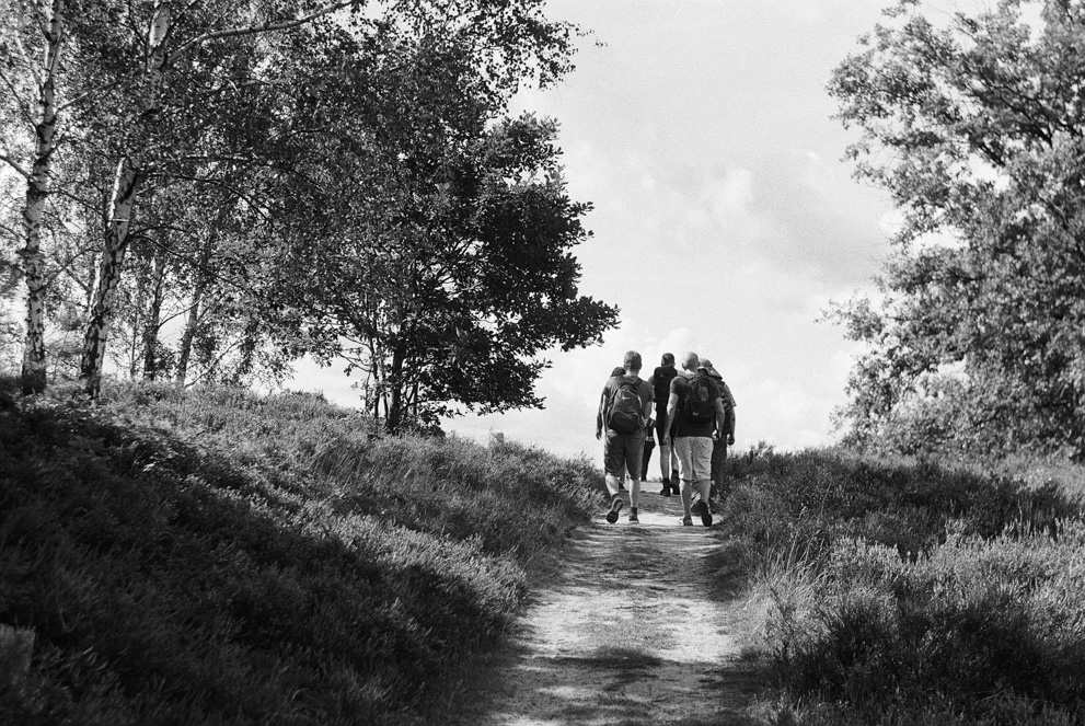 A group of hikers walking up a sunny hill. Shot on Ilford HP5 Plus